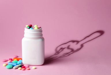 Doping concept. Plastic bottles with pills and silhouette of sportsman on pink background