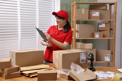 Photo of Parcel packing. Post office worker with clipboard at wooden table indoors