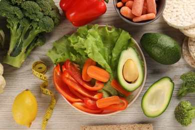 Photo of Healthy diet. Fresh vegetables and measuring tape on light wooden table, flat lay