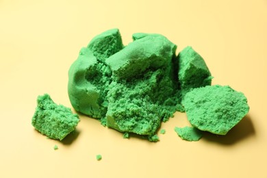 Photo of Green kinetic sand on beige background, closeup