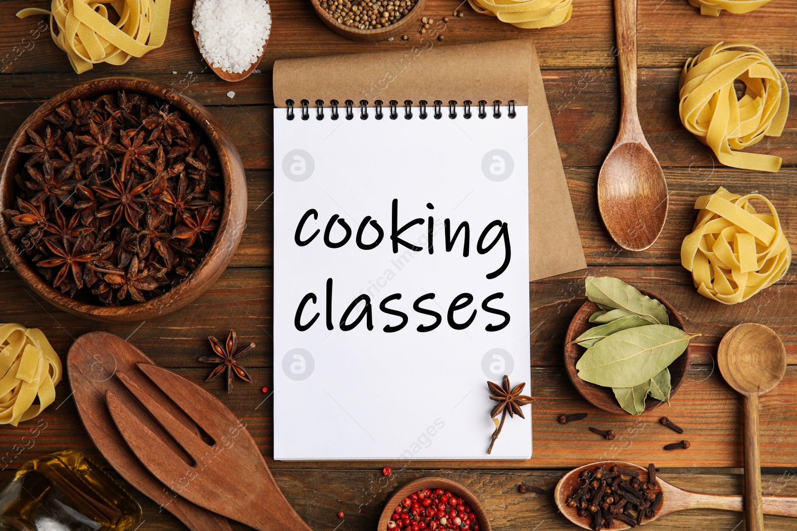 Image of Notebook with inscription Cooking Classes, raw pasta and spices on wooden table, flat lay