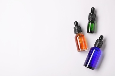 Photo of Bottles of essential oils on light background, top view. Cosmetic products