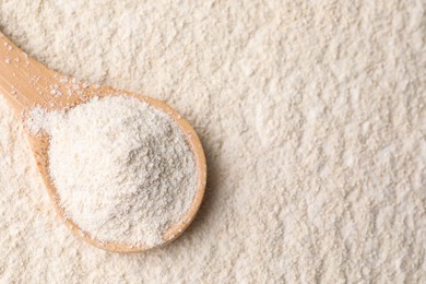 Photo of Quinoa flour and wooden spoon, top view. Space for text