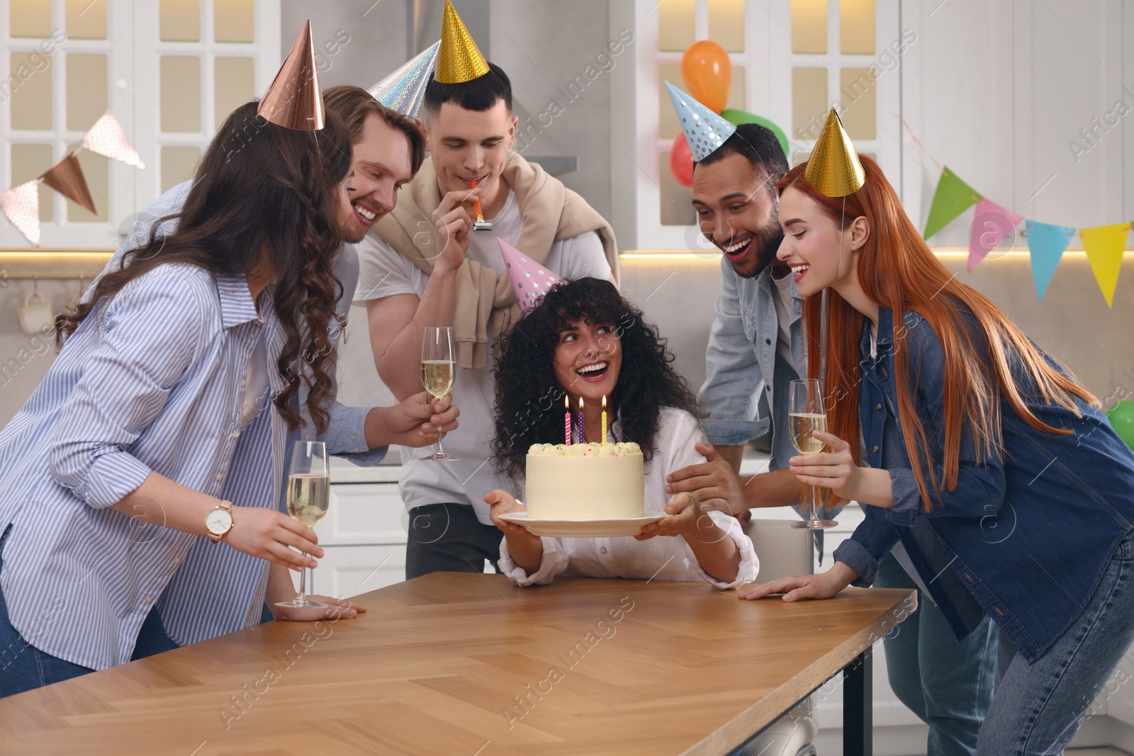 Photo of Happy friends with tasty cake celebrating birthday in kitchen