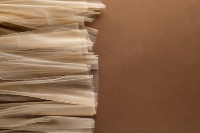 Photo of Beautiful tulle fabric on brown background, top view. Space for text