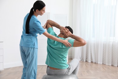 Photo of Orthopedist helping patient to do exercise in clinic. Scoliosis treatment