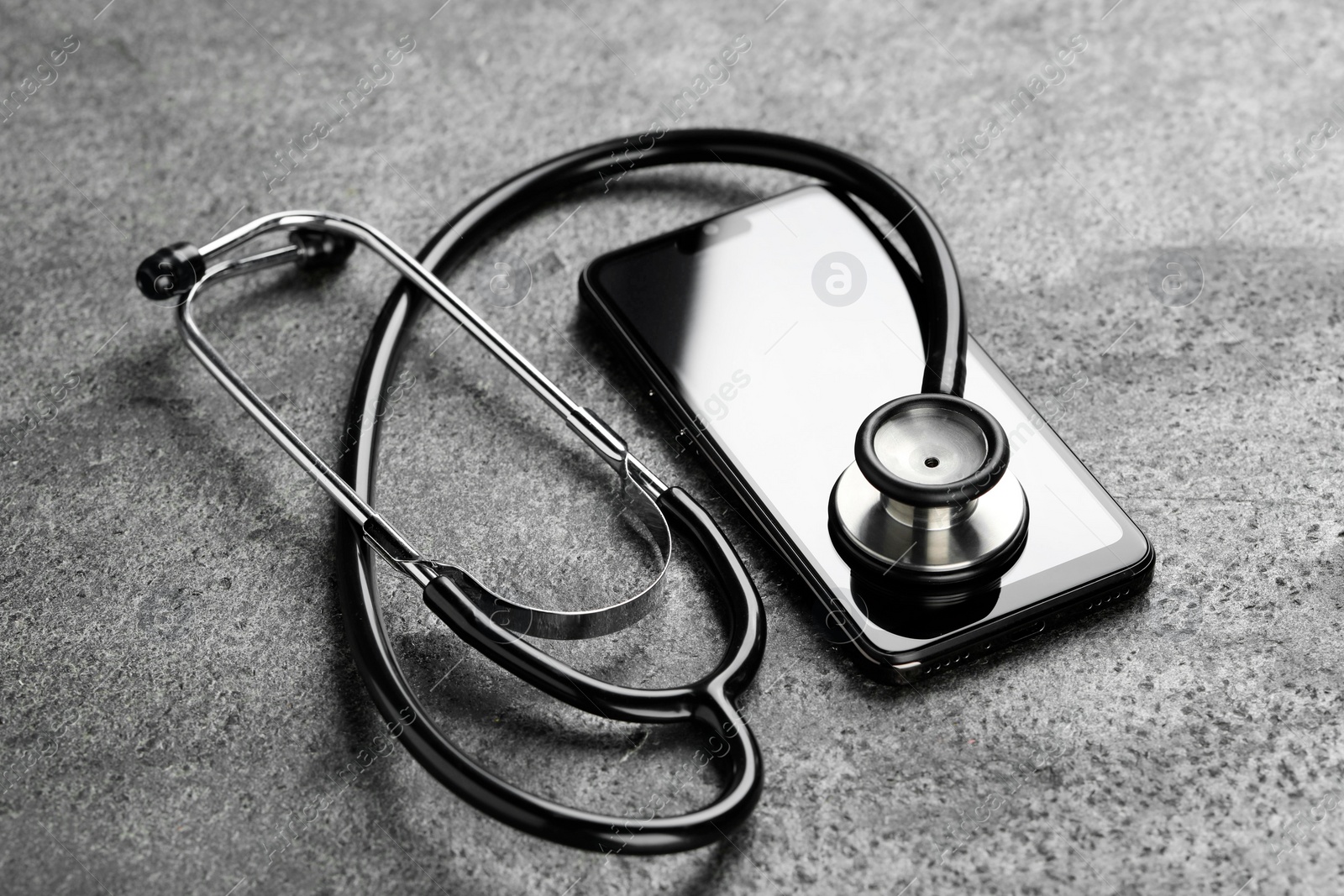 Photo of Modern smartphone and stethoscope on grey table