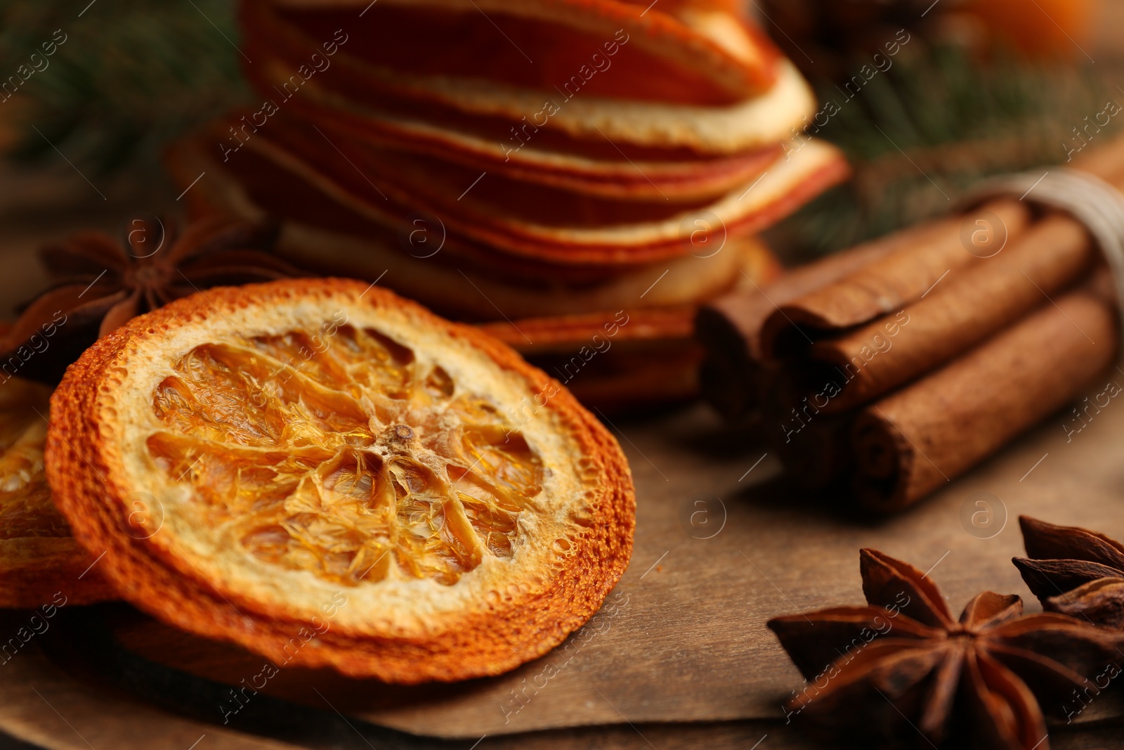 Photo of Dry orange slices, anise stars and cinnamon sticks on wooden board, closeup