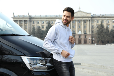 Photo of Handsome young man near modern car outdoors