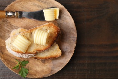 Photo of Tasty butter curls, knife and slices of bread on wooden table, top view. Space for text