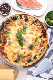 Delicious homemade quiche, ingredients and spatula on table, flat lay