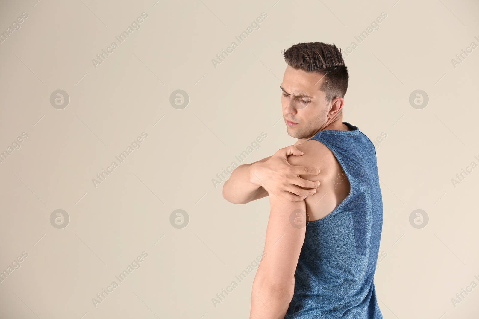 Photo of Man in sportswear suffering from shoulder pain on light background