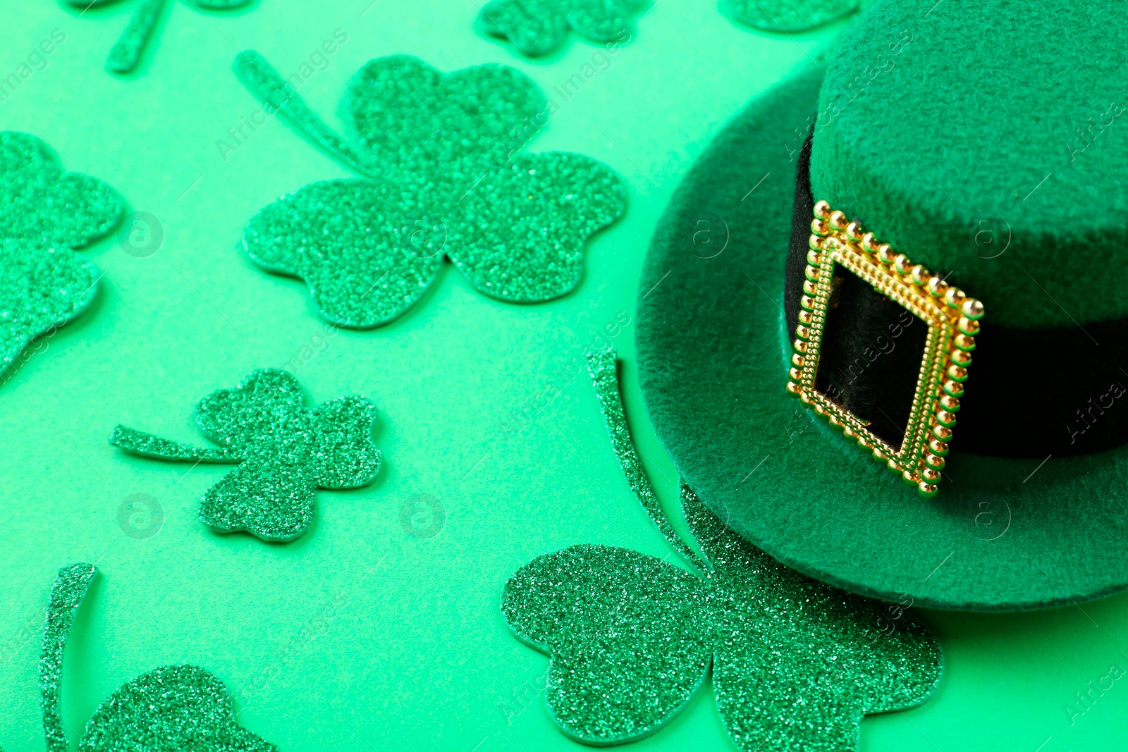 Photo of St. Patrick's day. Leprechaun hat and decorative clover leaves on green background