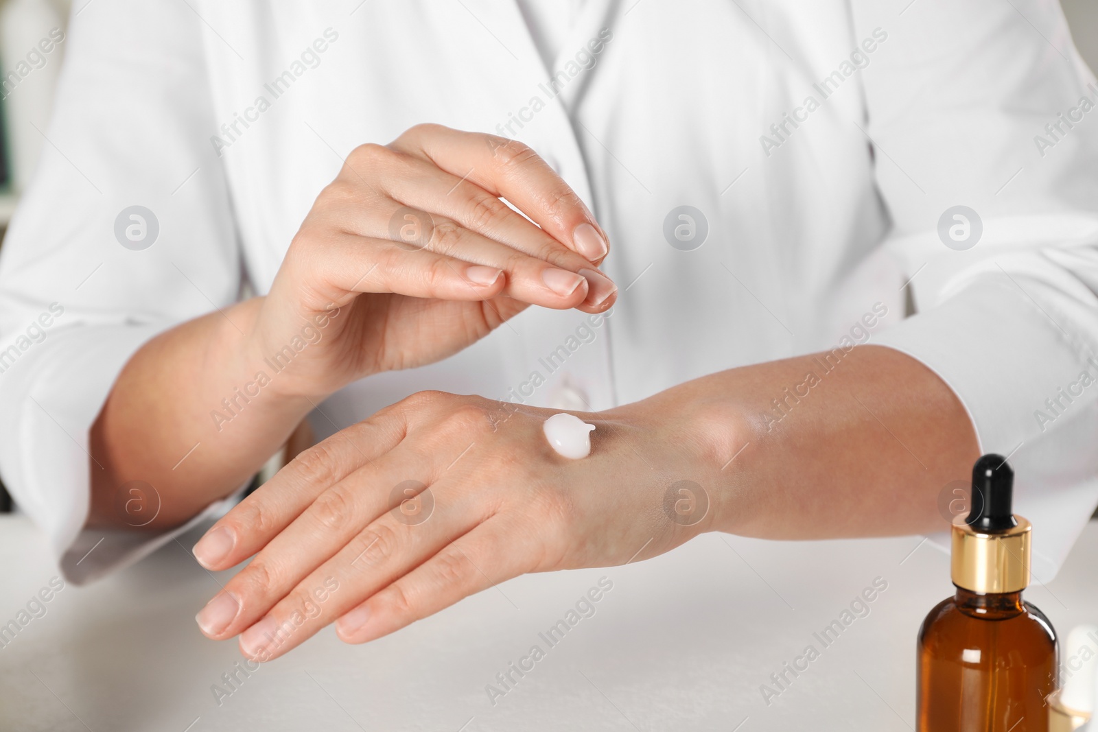 Photo of Dermatologist testing cosmetic product at white table, closeup