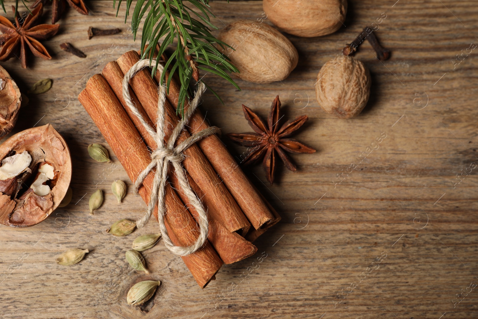 Photo of Different spices, nuts and fir branches on wooden table, flat lay. Space for text