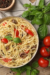 Photo of Delicious pasta with anchovies, tomatoes and spices on wooden table, flat lay