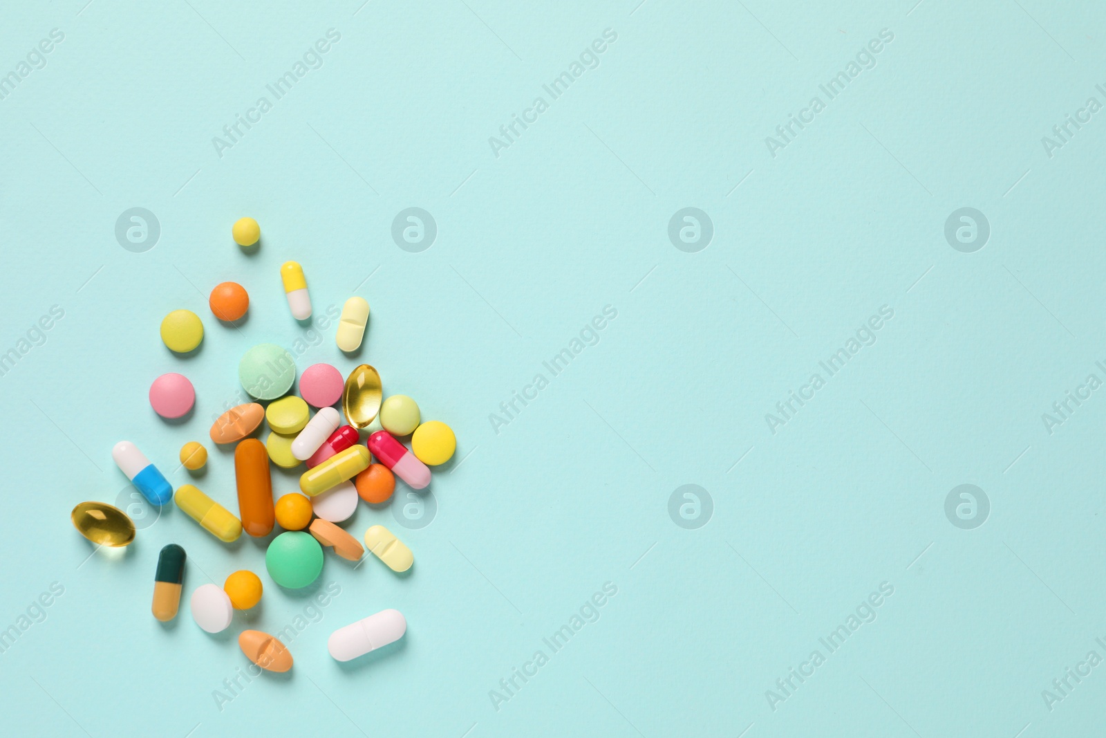 Photo of Many different pills on light blue background, flat lay. Space for text