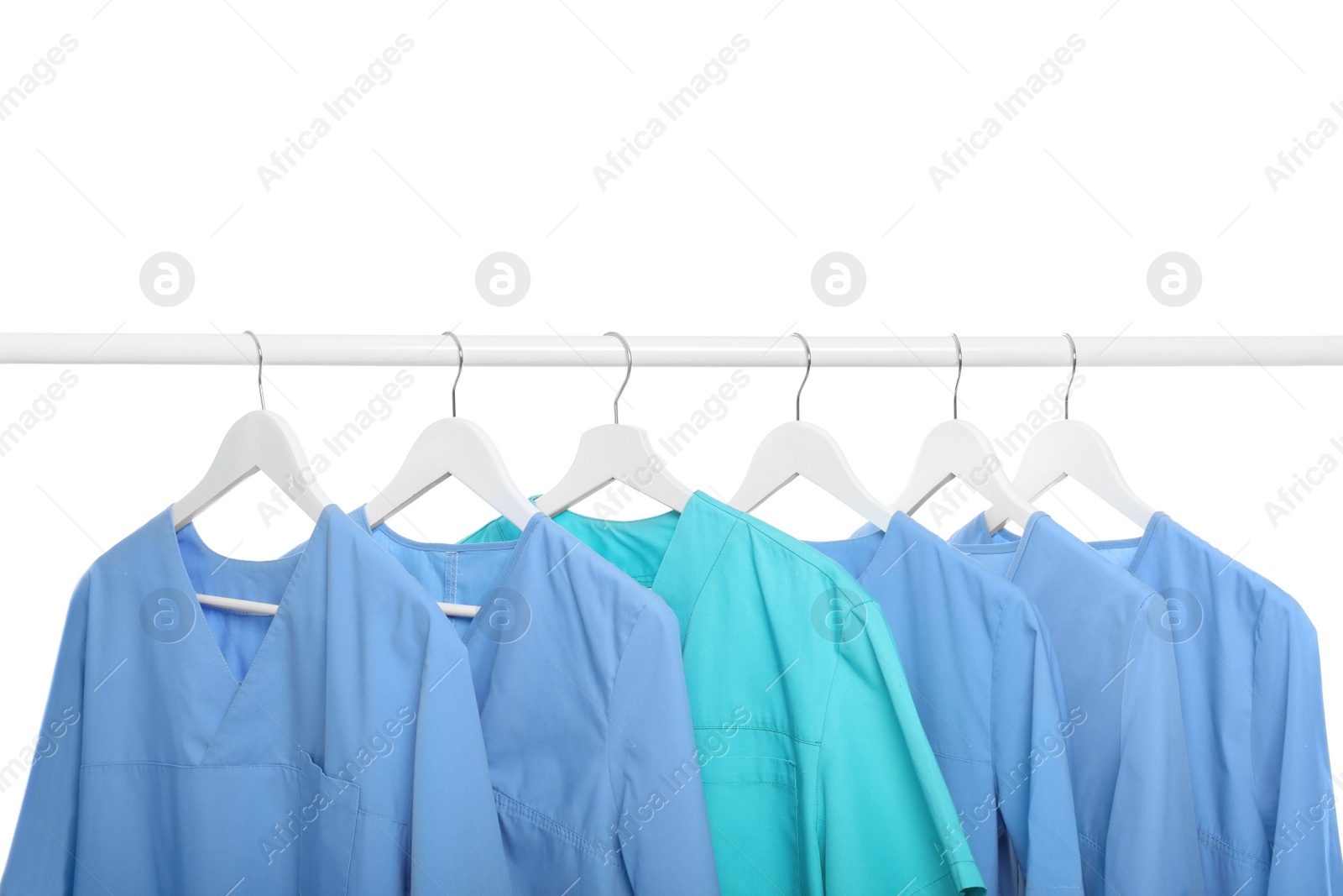 Photo of Light blue and turquoise medical uniforms on rack against white background