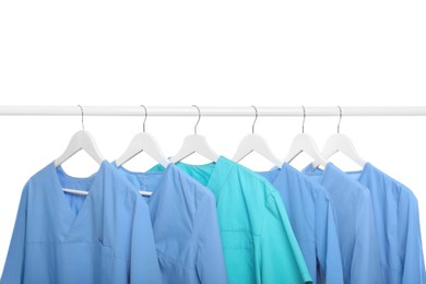 Photo of Light blue and turquoise medical uniforms on rack against white background