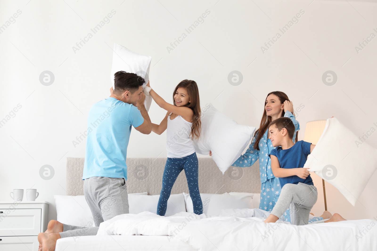 Photo of Happy family having pillow fight in bedroom