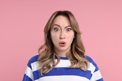 Portrait of surprised woman on pink background