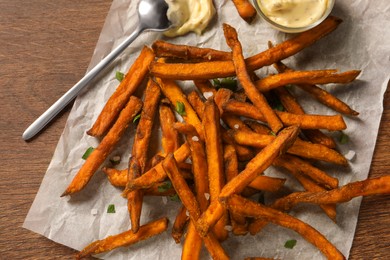 Photo of Delicious sweet potato fries and sauce on wooden table, top view