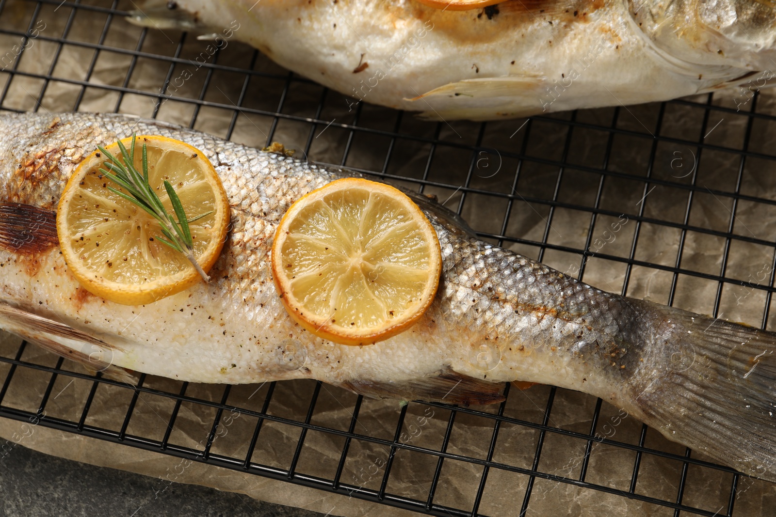 Photo of Baked fish with lemon on cooling rack, flat lay