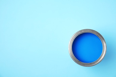 Photo of Open can of paint on blue background, top view. Space for text