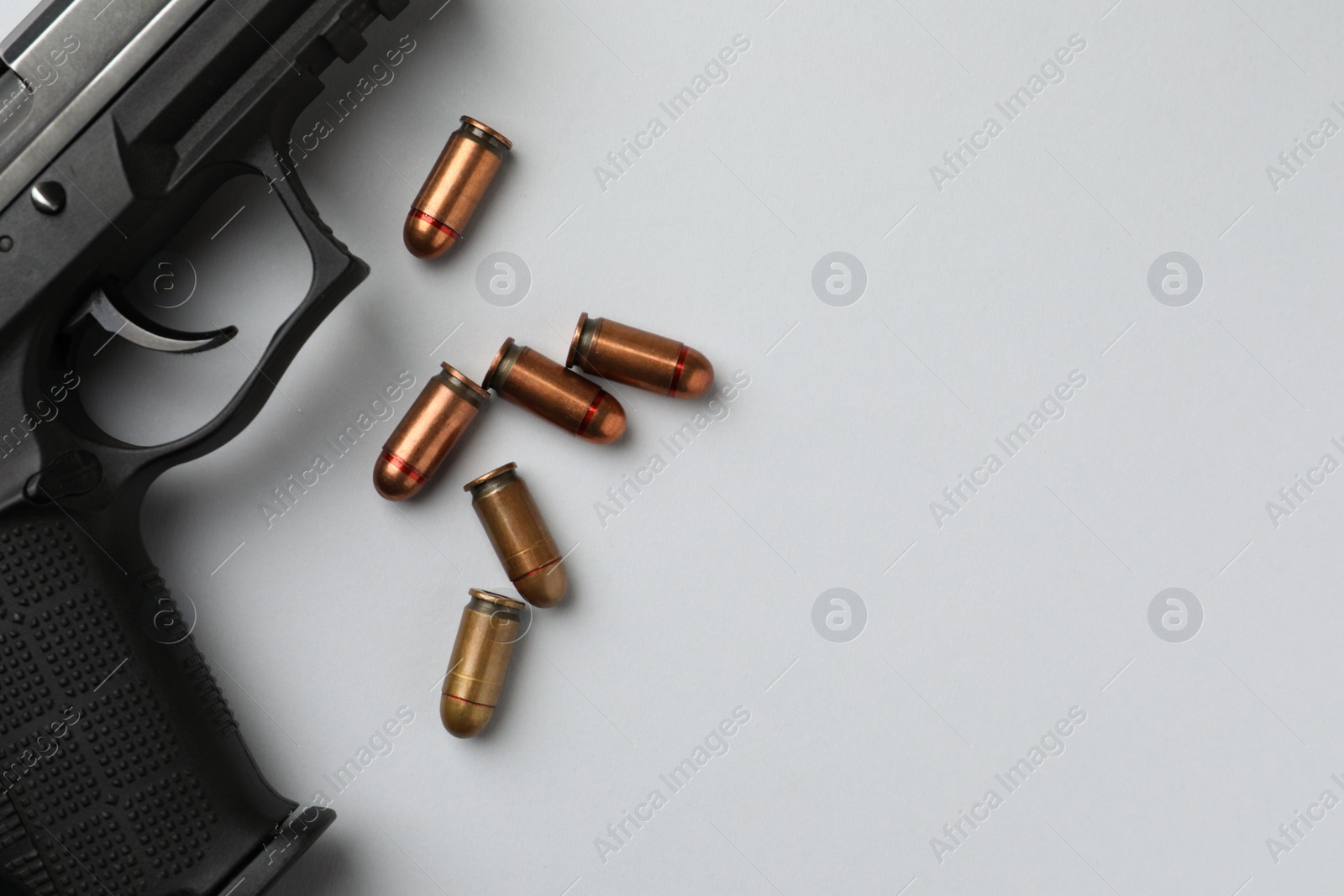 Photo of Semi-automatic pistol and bullets on light background, flat lay. Space for text