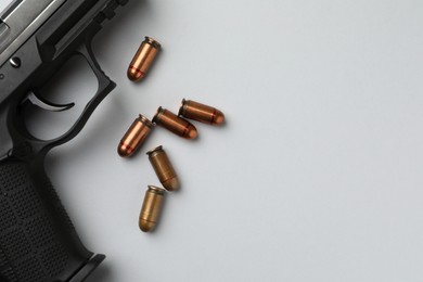 Photo of Semi-automatic pistol and bullets on light background, flat lay. Space for text