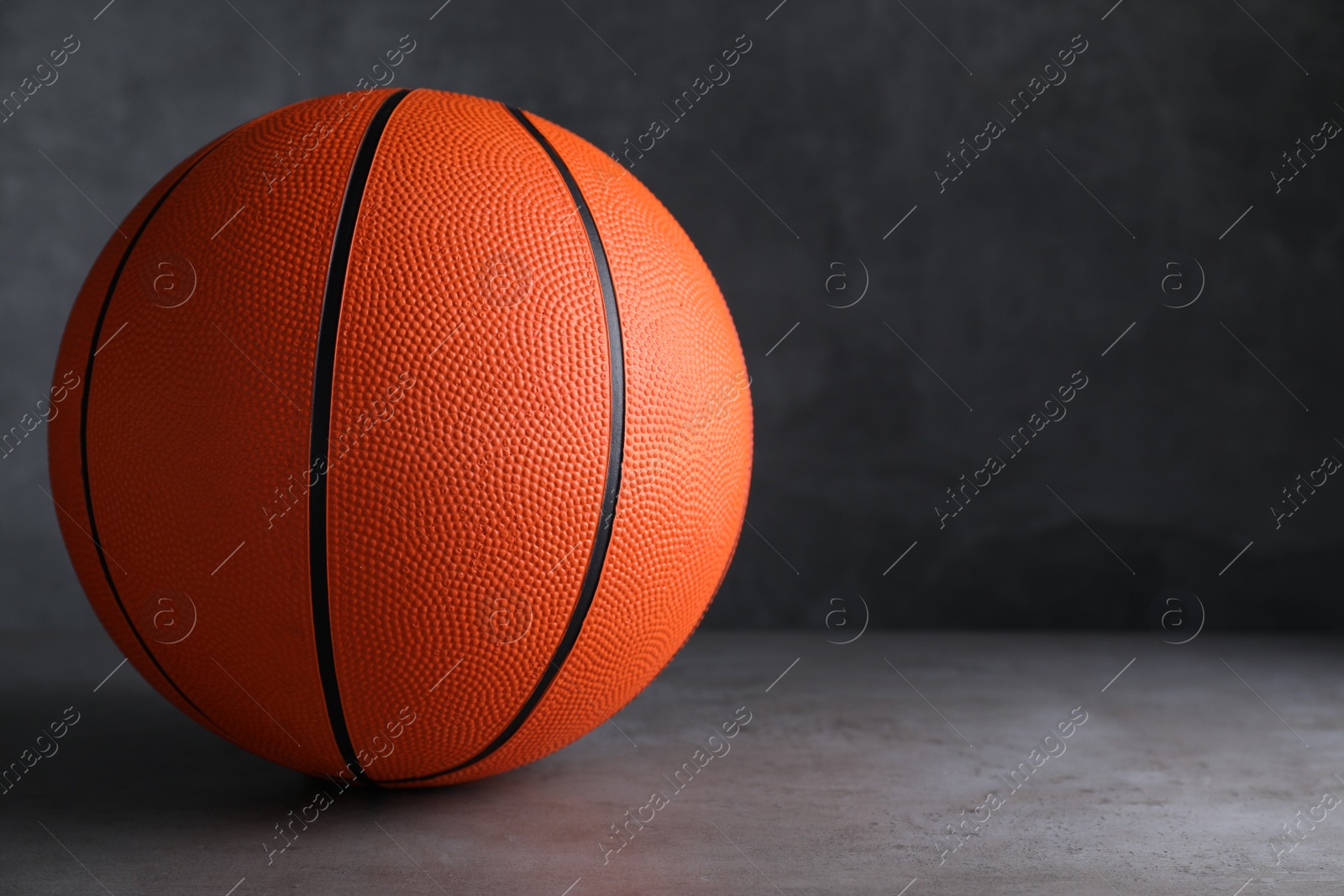 Photo of Orange ball on light grey table, space for text. Basketball equipment