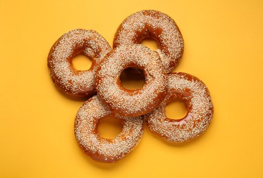 Delicious fresh bagels with sesame seeds on orange background, flat lay