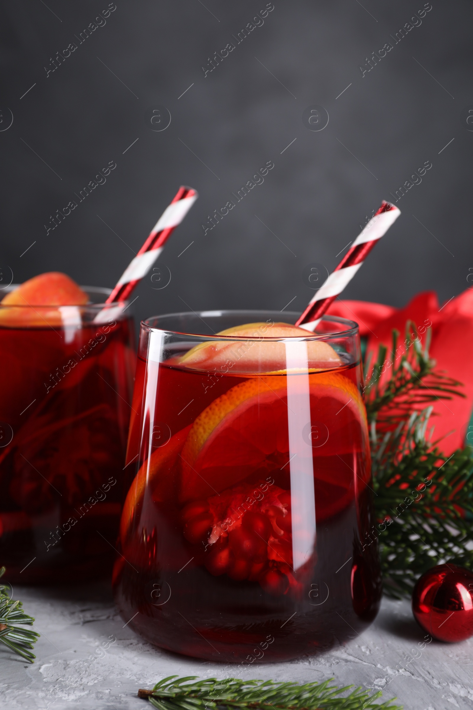 Photo of Delicious Sangria drink in glasses and Christmas decorations on grey textured table, closeup