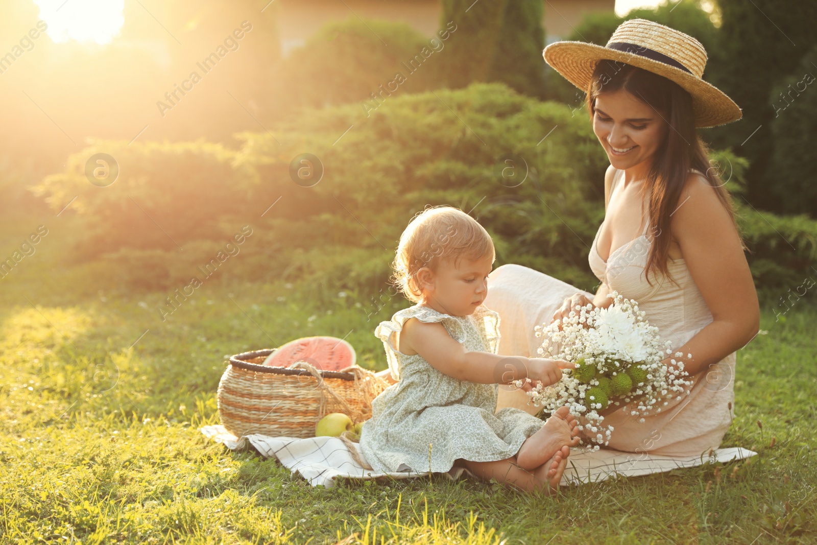 Photo of Mother with her baby daughter having picnic in garden on sunny day