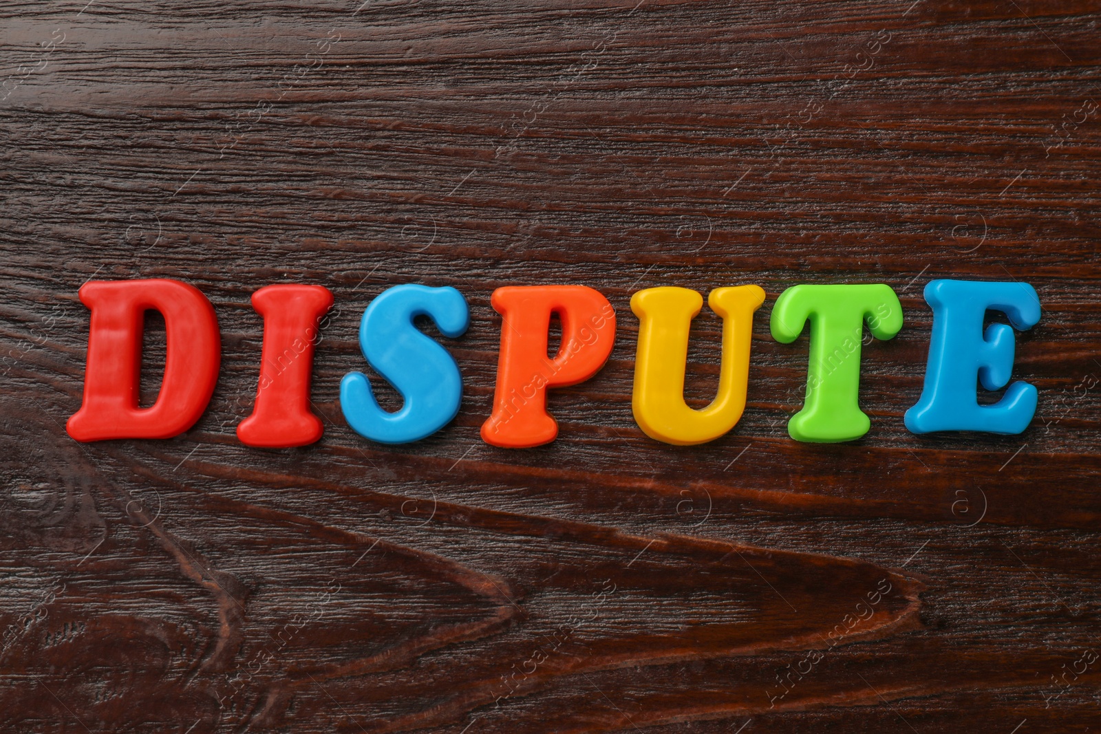 Photo of Word Dispute made of colorful letters on dark wooden table, flat lay