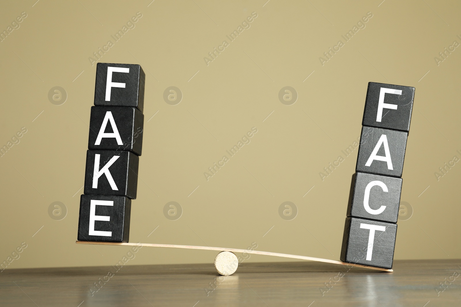 Photo of Wooden scale with words FAKE and FACT on table