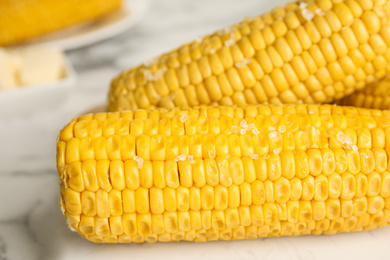 Photo of Delicious boiled corn with salt on table, closeup