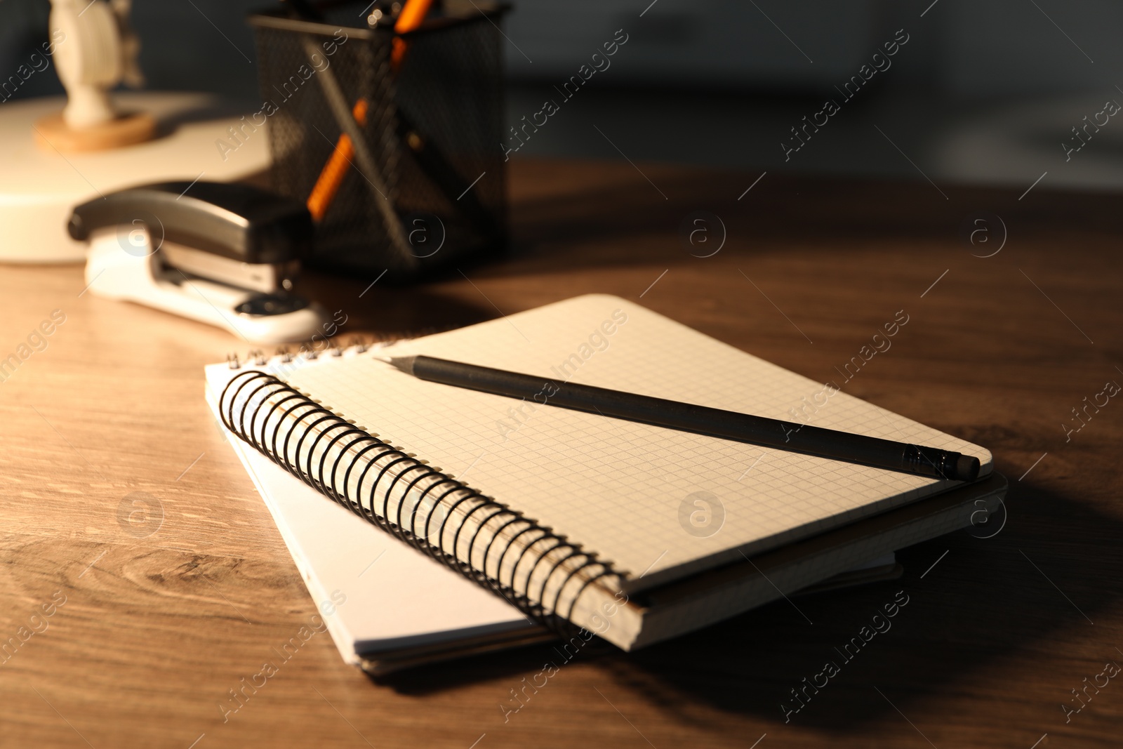 Photo of Notebooks and pencil on wooden table indoors, closeup