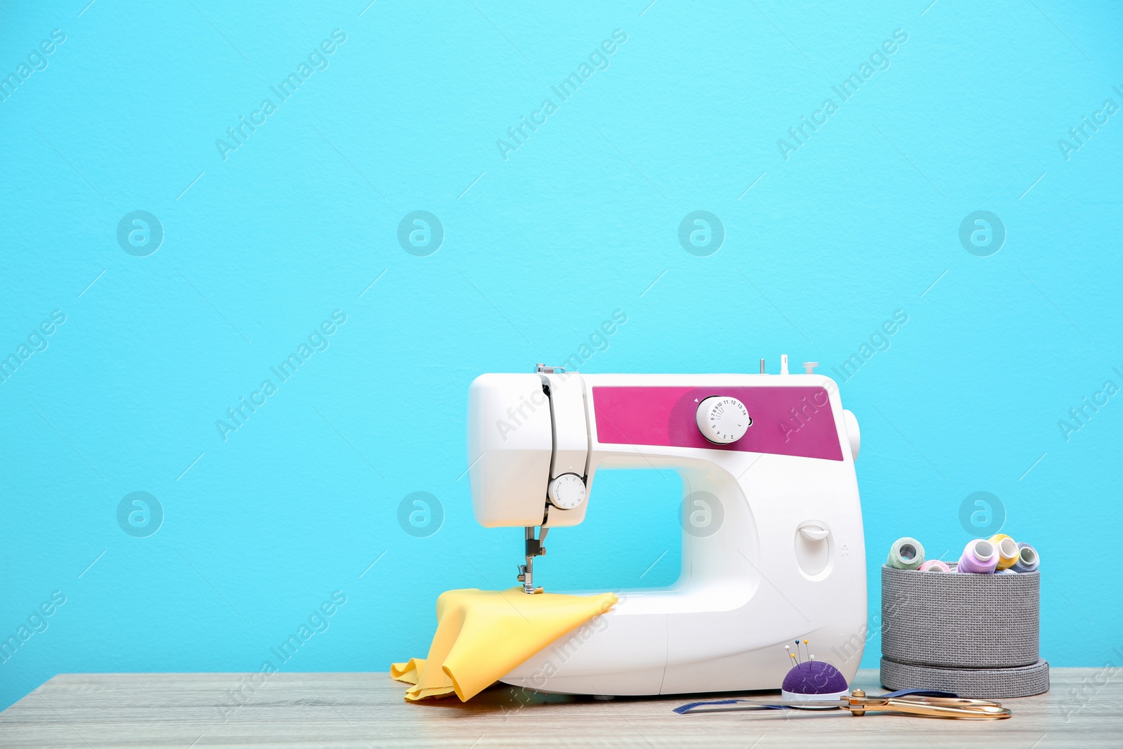 Photo of Sewing machine on table against color background