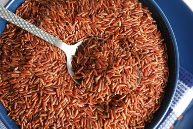 Bowl with uncooked red rice and spoon, closeup