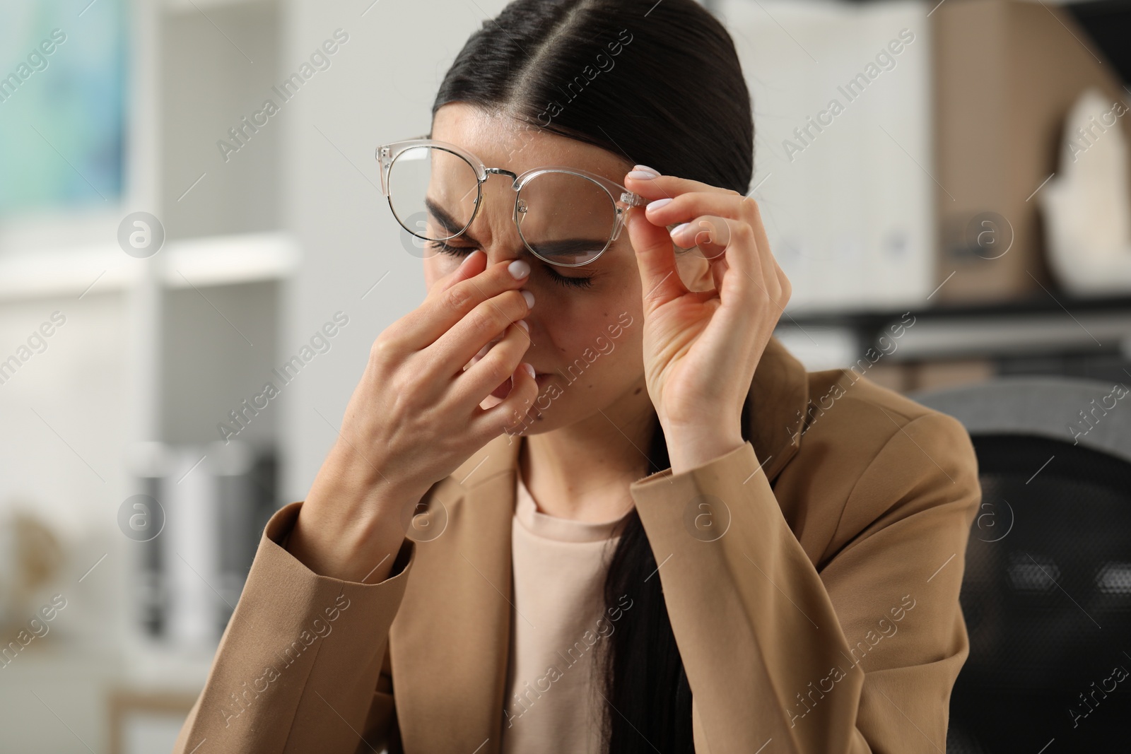 Photo of Woman suffering from headache at workplace in office