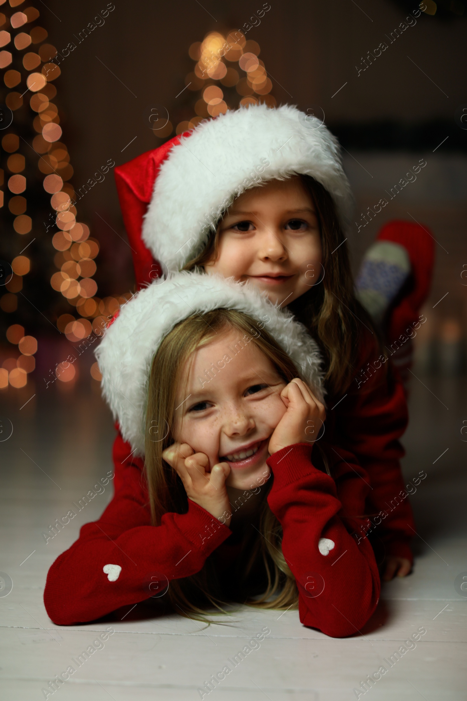 Photo of Cute little children wearing Santa hats at home. Christmas time