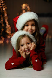 Photo of Cute little children wearing Santa hats at home. Christmas time