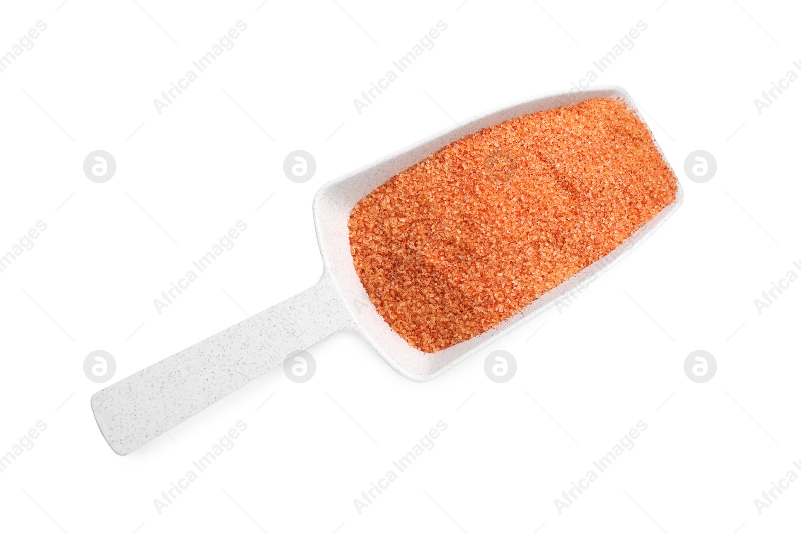 Photo of Orange salt in scoop isolated on white, top view