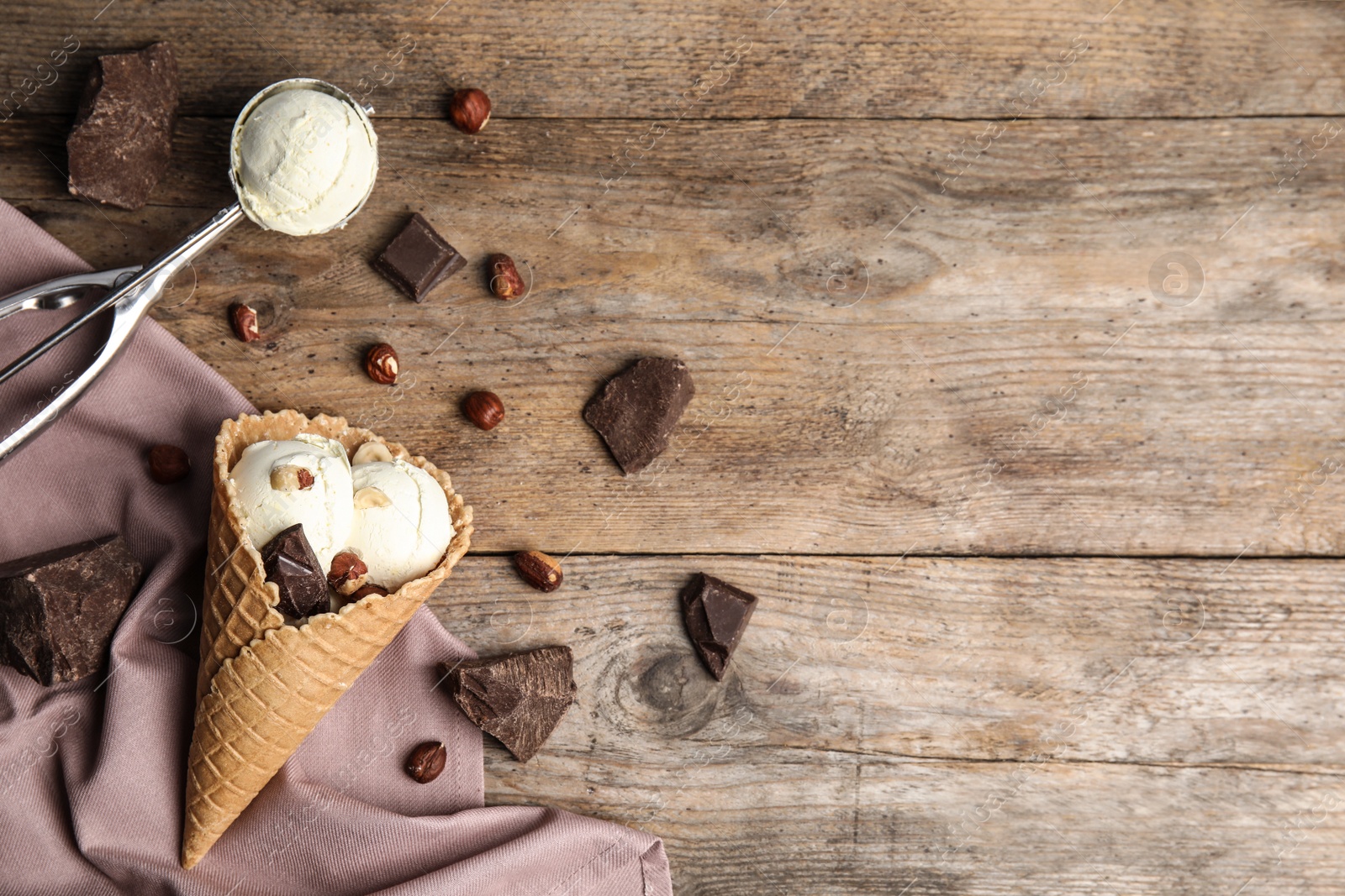 Photo of Flat lay composition with delicious ice cream in waffle cone on wooden table, space for text