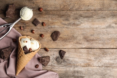 Flat lay composition with delicious ice cream in waffle cone on wooden table, space for text