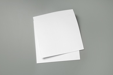 Photo of Blank paper sheets for brochure on grey background, top view. Mock up