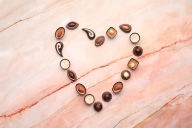 Photo of Heart made with delicious chocolate candies on marble table, top view