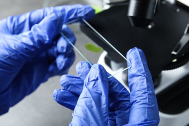 Medical assistant using microscope at table, closeup