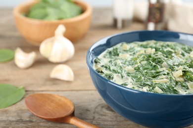 Photo of Tasty spinach dip in bowl on wooden table